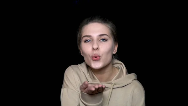 Young beautiful woman blowing kiss isolated over a black background. Cute lovely young woman with hair in knot blow air kiss with pouted lips — Stock Photo, Image