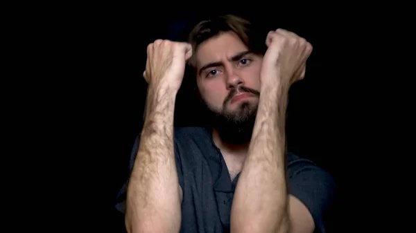 Joven hombre hipster barbudo aislado sobre fondo negro mientras escucha música y baile. Hombre joven atractivo en suéter gris que se divierte sobre fondo negro — Foto de Stock