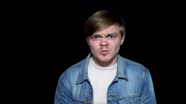 Stäng för arg, arg, pissed off, stilig man. Hipster hane med skägg i blå jeansjacka gör arg, galna ansikte uttryck, isolerad på svart bakgrund. — Stockfoto