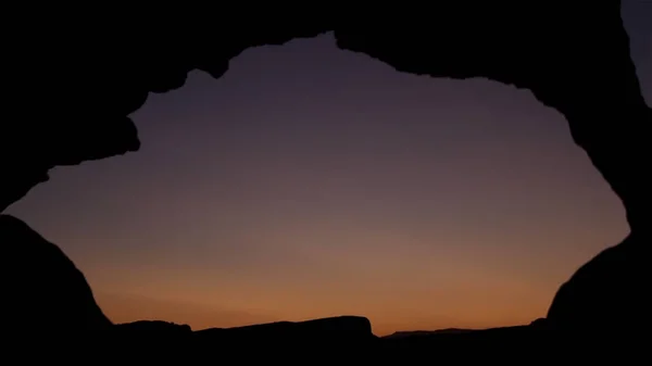 黄昏时分, 在海墙上看日落。拍摄。看着夕阳穿过岩石的洞。岩石洞的特写。通过古老的窗口的日落 — 图库照片