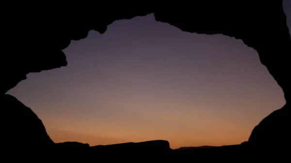 黄昏时分, 在海墙上看日落。拍摄。看着夕阳穿过岩石的洞。岩石洞的特写。通过古老的窗口的日落 — 图库照片