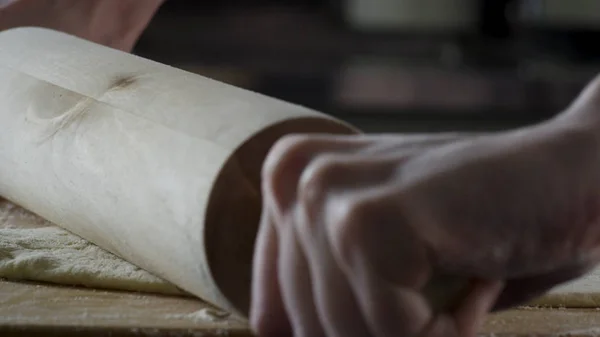 Hombre extendiendo la masa en la mesa de la cocina, de cerca. Escena. El cocinero enrolla un trozo de masa en la mesa de la cocina con un rodillo. Vista de cerca. Concepto de cocina y comida casera — Foto de Stock