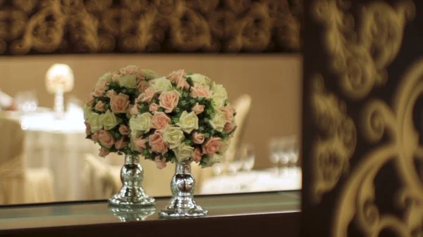 Ramo de flores artificiales en un restaurante de lujo. Escena. Decoraciones florales en la mesa en el restaurante el día de la boda. Un hermoso ramo de flores en un jarrón transparente en el fondo de la — Foto de Stock