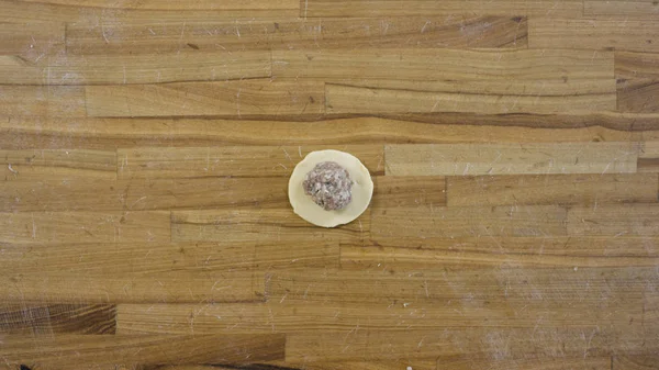 Bovenaanzicht op mannelijke handen dumplings maken, Man maakt deeg en vlees van knoedels. Thuis koken, maken handen vlees dumplings op een houten tafel. Dumplings, meel, prei, deegroller, op houten tafel. — Stockfoto