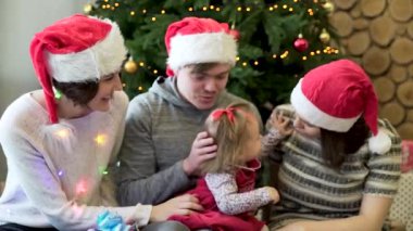 Arkadaşlar oyun küçük kız, hediyeler sparkles ve Noel ağacı arka plan ile. Noel tatili. Noel aile portresi.