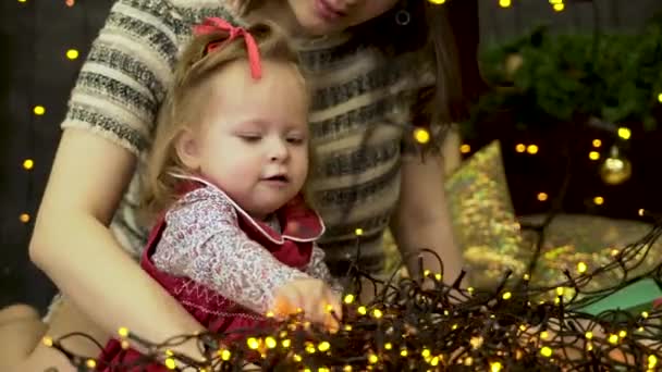 Feliz familia de la madre y el bebé pequeña hija jugando en el invierno para las vacaciones de Navidad, destellos de fondo. Feliz familia madre e hija en Navidad — Vídeo de stock