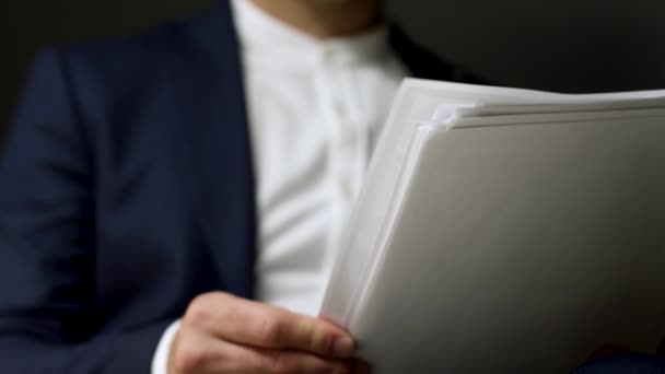 Extreme close up for a man during reading contract and turning the page, isolated on grey background. Man holding an turning to the next page important paper documents, business concept. — Stock Video