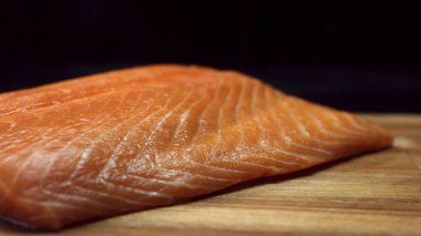 Siyah arka plan üzerine izole ahşap kesme tahtası üzerinde leziz, taze somon steak için kapatın. Çiğ kırmızı balık fileto Ahşap Doğrama tahtası, pişirme, Gıda Porno kavramı.