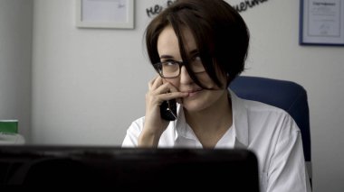 Dizüstü bilgisayar ekranına bakarak beyaz ofis duvar arka plan üzerinde beyaz gömlekli güzel bir genç kadın portresi kapatın. Modern iş kadını onun çalışma yerine bilgisayar ekranı önünde çalışma.