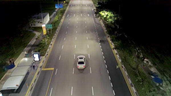 Singapur - 25 de septiembre de 2018: Vista superior de la calle con carretera de intersección y personas cruzando la calle por la noche. Le dispararon. Vista aérea del cruce de la ciudad con coches y personas en el cruce de cebra durante —  Fotos de Stock