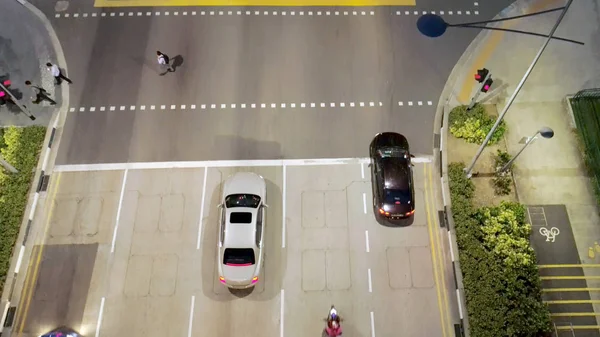 Singapura - 25 de setembro de 2018: Vista superior da rua com estrada de cruzamento e pessoas que cruzam a rua à noite. Atingido. Vista aérea da encruzilhada da cidade com carros e pessoas na travessia de zebra durante — Fotografia de Stock