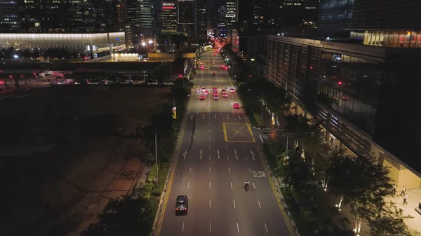 Κάτοψη του δρόμου με αυτοκίνητα και σύγχρονα κτίρια σε μεγάλη κινεζική πόλη τη νύχτα. Βολή. Νύχτα Αεροφωτογραφία του κέντρου της πόλης, με το δρόμο, κινείται αυτοκίνητα, τα φώτα των ουρανοξυστών, έννοια ζωή νύχτας. — Φωτογραφία Αρχείου