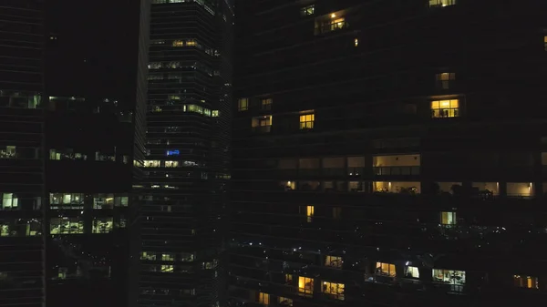 Singapour - 25 septembre 2018 : Vue frontale de la façade nocturne du bâtiment avec beaucoup de fenêtres éclairées. Fusillade. Façade du bâtiment multi-étages de verre et d'acier, bureaux et travailleurs à l'intérieur — Photo