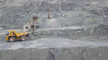 Tarak ve damperli kamyon Taş Madencilik Sanayi gri bir taş ocağı cevher yüklenirken. Hisse senedi. Ağır madencilik Ekskavatör rock cevher döküm gövdeli büyük incelemesi kamyonete, taş ocağı ekipman yükler..