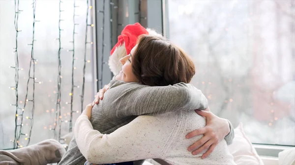 Birlikte Noel ve yeni yıl kutlama sırasında hediye alışverişi çift için kapatın. Adam Santa Claus şapka ve renkli kağıt ambalaj ve sarılma, kış tatil kavramı hediye vermek kadın. — Stok fotoğraf