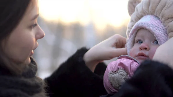 Primer plano para feliz, hermosa madre tocando el sombrero de niña encantadora en el parque de invierno, familia al aire libre. Retrato de mamá alegre con su lindo hijo en un paseo de invierno en el parque . —  Fotos de Stock