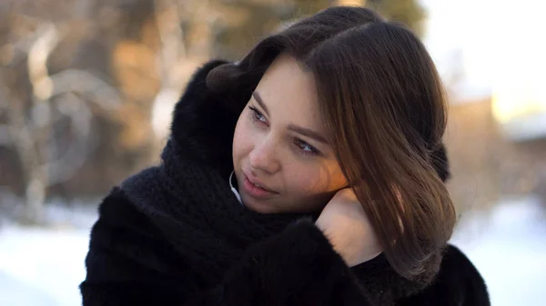 Stylowy, młoda kobieta z krótkie, ciemne włosy, zakładanie białe słuchawki podczas spaceru w parku zimowym. Ładna, atrakcyjna dziewczyna noszenia słuchawek podczas spaceru na świeżym powietrzu zimą. — Zdjęcie stockowe