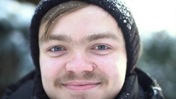 Muotokuva komea, iloinen mies viikset pukeutunut talvivaatteita lunta hänen kasvonsa. Lähikuva vaalea mies siniset silmät hymyillen aurinkoinen, talvi päivä . — kuvapankkivalokuva
