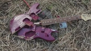 Solmuş saman, üstten görünüm yalan kırık mor gitar için kapatın. Hisse senedi. Kırık elektro gitar parçaları Menekşe güverte ve solmuş çim zemin üzerine kahverengi boyun.