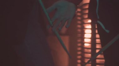 Izgara Tüylü, kırmızı ateş arka plan üzerinde elinde dönen adam. Sahne. Parmaklarını sopaları dönen genç adam için yakın çekim.