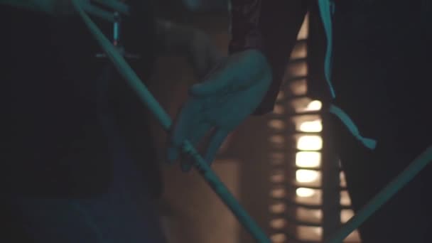 Close up van de man met trommel stok tussen vingers en het spinnen, rock muziek concept. Jonge drummer met een roterende trommel stok in zijn hand op rood vuur lichte achtergrond wazig. — Stockvideo