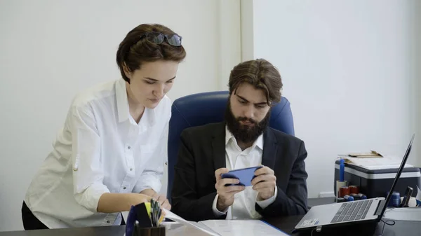 Boss spelar telefonen när anställde visar honom dokument och ber honom att underteckna dem. — Stockfoto