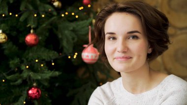Yeni yıl kutlama Noel ağacı önünde bir güzel, gülümseyen, esmer kız portresi. Genç, güzel dekore edilmiş Ladin zemin üzerine kısa, koyu saçlı kadın.