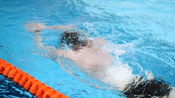 Primer plano para nadador profesional en mothion lento mientras que la carrera de natación en la piscina cubierta. Entrenamiento de deportistas, nadar en la piscina . —  Fotos de Stock