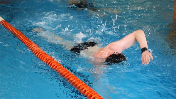 Primer plano para nadador profesional en mothion lento mientras que la carrera de natación en la piscina cubierta. Entrenamiento de deportistas, nadar en la piscina . —  Fotos de Stock