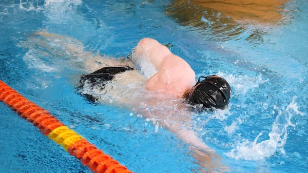 Primer plano para nadador profesional en mothion lento mientras bucea en la piscina cubierta. Entrenamiento de deportistas, buceo bajo el agua en la piscina . —  Fotos de Stock