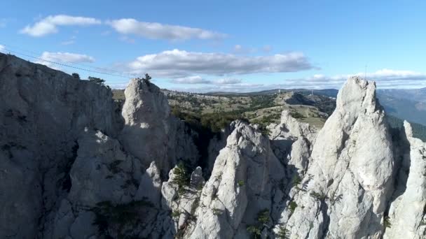 Aerial panoramic view of mountain cableway, above green trees on blue, cloudy sky background. Shot. Fascinating cliffs covered with coniferous forest in a summer sunny day. — Stock Video