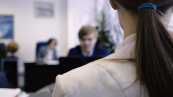 年轻女子肩上的办公室特写 办公桌办公室年轻员工侧对肩的后视图 — 图库视频影像