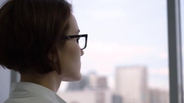 Yakın çekim işkadını vasıl pencere. Üzgün yorgun görünümlü bir şey hakkında office düşüncesinde pencereden dışarı çekici işkadını görünüyor