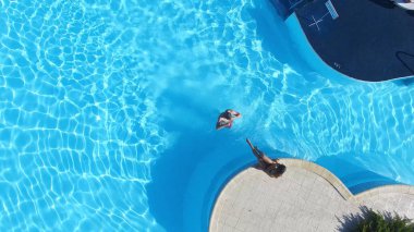 Üstten görünüm genç çift resort yüzme havuzunda rahatlatıcı. Sahne. Havuzun lüks otel bir yüzme çift üstten görünüm