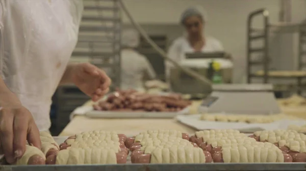 Närbild av bearbetning i livsmedelsindustrin. Scen. Arbetstagare på matfabriken producera korv i degen — Stockfoto