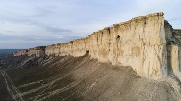 Ovanifrån av ren klippa. Skott. Fantastisk panoramautsikt över branta vita rock med erosion vid dess fot. Vita berget med brant sluttning och spridning av småsten på fot, med ovanlig ränder — Stockvideo