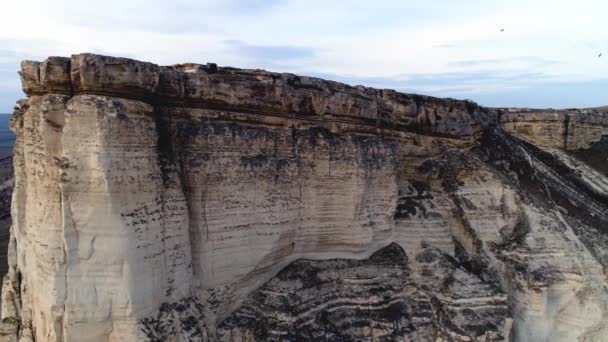 Vista superior del acantilado. Le dispararon. Increíble vista panorámica de roca blanca empinada con erosión a sus pies. Montaña blanca con pendiente pronunciada y manchas negras en su superficie contra el cielo azul — Vídeo de stock