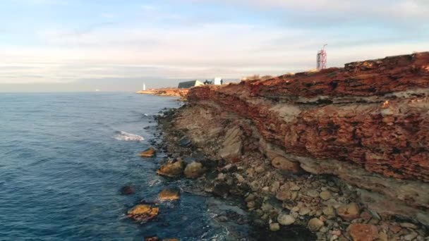 Barriera rocciosa di riva. Gli hanno sparato. Vista dall'alto della costa di scogliere rocciose di mare di rosso con buchi e pietre incollate. Bel mare blu va e viene a ondate — Video Stock