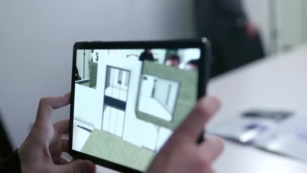 Виртуальный чертеж дома на планшете. На складе. Бизнесмен держит планшет с проектом виртуальной реальности дома в зале заседаний. Цифровая 3D модель проекта недвижимости показана на гаджете — стоковое видео