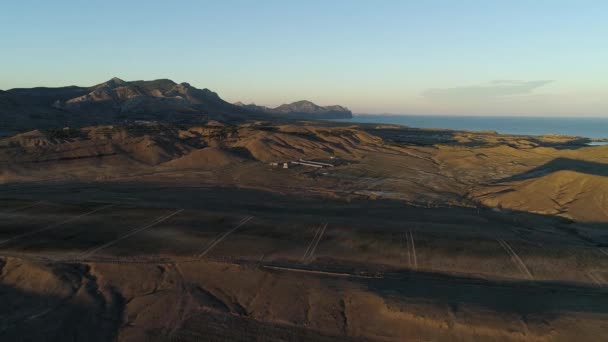 Antenne für schöne Landschaft von grünem Feld im Sonnenuntergang auf blauem Meer und bewölktem Himmel Hintergrund. Schuss. goldenes Tal und blaues Meer mit wolkenverhangenem Himmel, wunderbare Natur per Drohne. — Stockvideo