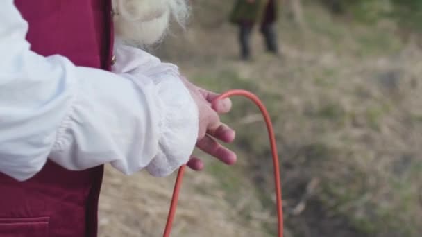 Técnica de pesca antiga, pescador em traje antiquado recebendo uma rede de pesca. Estoque. Homem de roupas velhas de maneira rococó puxando uma rede de pesca, de pé na margem do rio em um dia ensolarado . — Vídeo de Stock