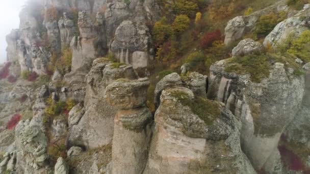 Stenen van ongebruikelijke vormen op de berg bedekt met wolken mist. Schot. Luchtfoto voor mistige dag in de bergen en de mooie vorm stenen met geel, herfst bomen en struiken. — Stockvideo