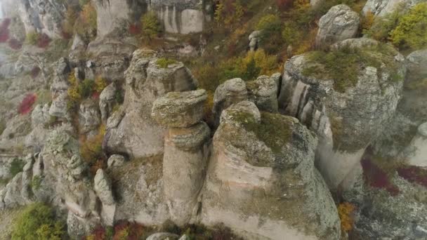 Piedras de formas inusuales en la montaña cubiertas de nubes de niebla. Le dispararon. Vista aérea para un día de niebla en las montañas y hermosas piedras de forma amarilla, árboles de otoño y arbustos . — Vídeo de stock