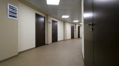 Boş, açık bej ile koridor yuvarlak duvarlar ve kapalı, koyu kahverengi kapılar. Ofis Binası içinde yanan bir koridor boyunca kapalı kapılar.