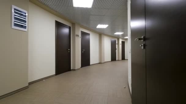空荡荡的圆形走廊, 有浅米色的墙壁和封闭的深棕色门。在办公楼一条灯火通明的走廊上关闭大门. — 图库视频影像