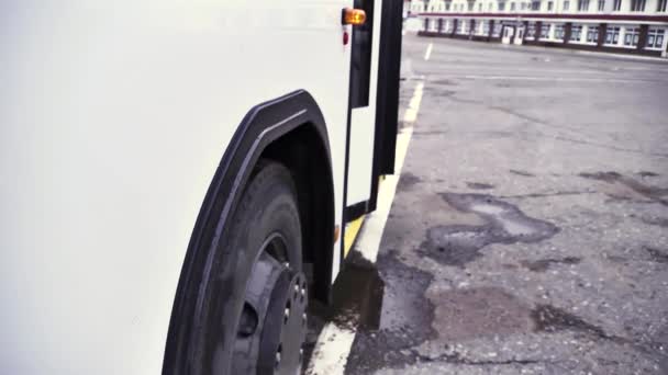 Oldalnézetből a fehér busz nyitható ajtó és busz kerék aszfalt szürke háttéren. Az utas busszal, nyitott ajtó villogó fény és a kerék, kereskedelmi szállítás kerekek koncepció közelről.