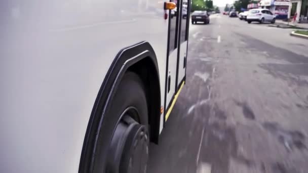 Jantlar ve lastikler görünümünden şehir etrafında sürme otobüsün yolda kapatın. Sahne. Beyaz veri yolu sokakta şehir merkezinde aşağı taşır. — Stok video
