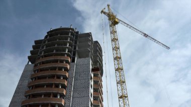 Yüksek katlı Mavi gökyüzü bulutlu karşı bir vinç ile bina inşaatı. Sahne. Alt görünümü. çok katlı bina ile çöp bina ile boş pencere eşiği inşaat sürecinde gri