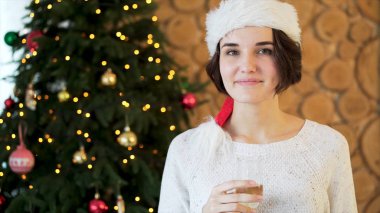 Kazak ve çorap bir kadeh şampanya ile Noel ağacı arka plan üzerinde oturan kız. Kız onun elinde tutan bir bardak şampanya Noel kutluyor.