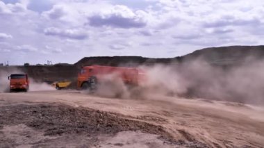 Büyük, kırmızı toz uçan ile bir kum ocağında hareketli Ekskavatör. Sahne. Kalın bir toz geride bırakarak açık döküm ocağı Damper kamyonlara yükleme ağır.